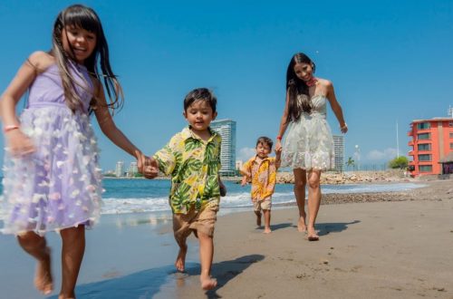 Cheerful family playing and running on a sunny beach, enjoying a vacation day together.