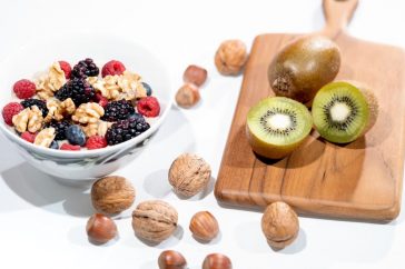 A vibrant bowl of mixed berries, walnuts, and kiwi on a cutting board. Perfect for a healthy breakfast.