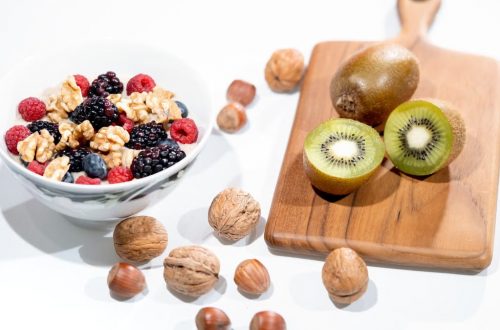 A vibrant bowl of mixed berries, walnuts, and kiwi on a cutting board. Perfect for a healthy breakfast.