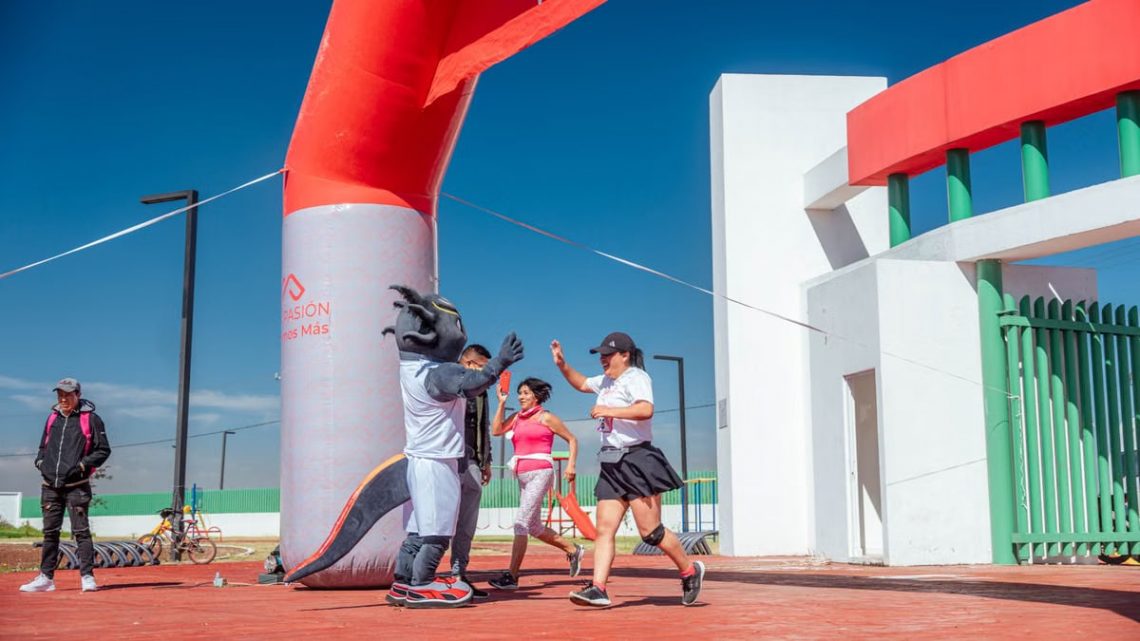 Runners celebrate with high fives at a marathon finish line under a clear blue sky.