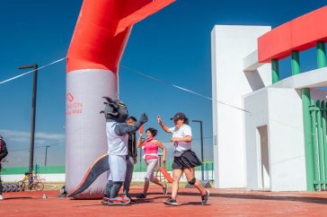 Runners celebrate with high fives at a marathon finish line under a clear blue sky.