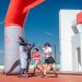 Runners celebrate with high fives at a marathon finish line under a clear blue sky.